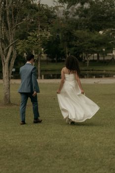 Bride and groom walking in a park, creating a romantic and elegant moment.