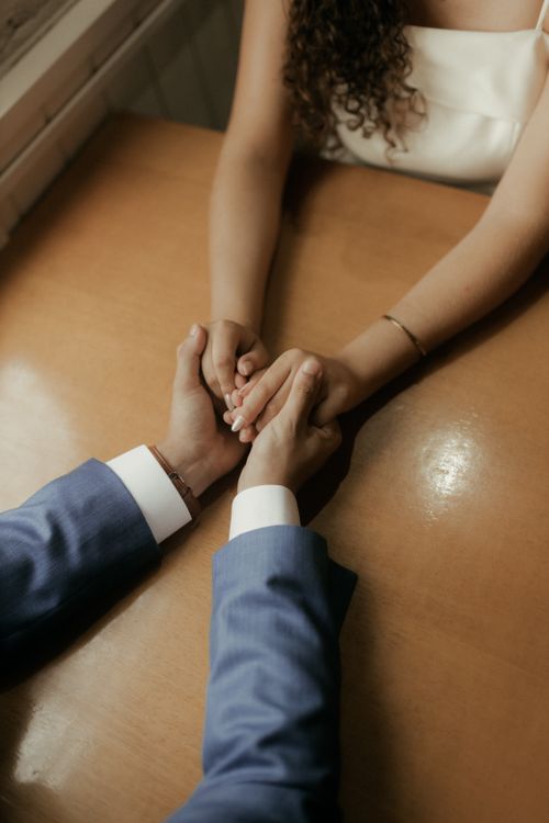 Free Close-up of a couple holding hands across a table, symbolizing love and connection. Stock Photo
