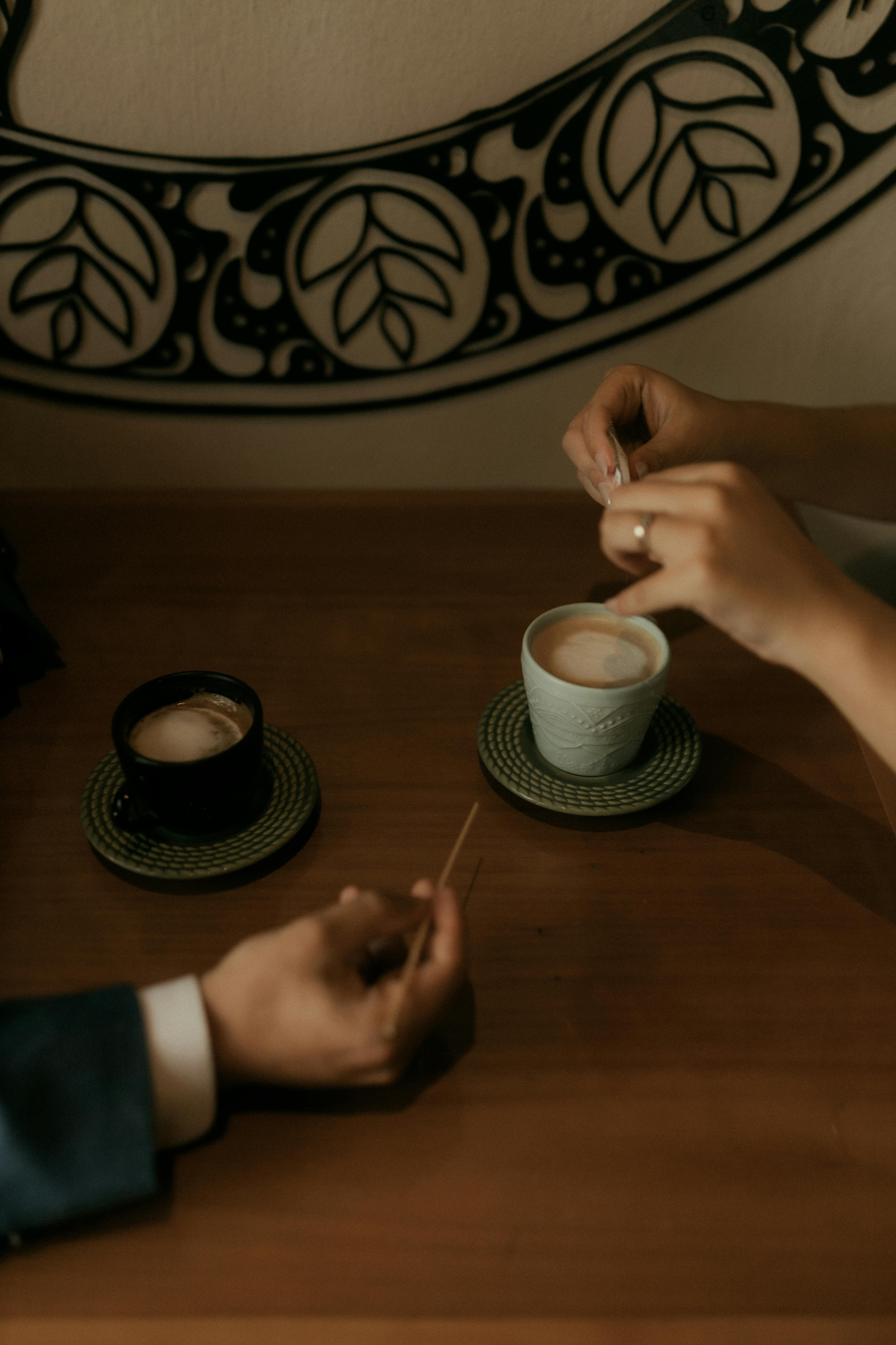 Gratis Una coppia si gode un momento di relax sorseggiando un caffè e un cappuccino in un ambiente caldo. Foto a disposizione