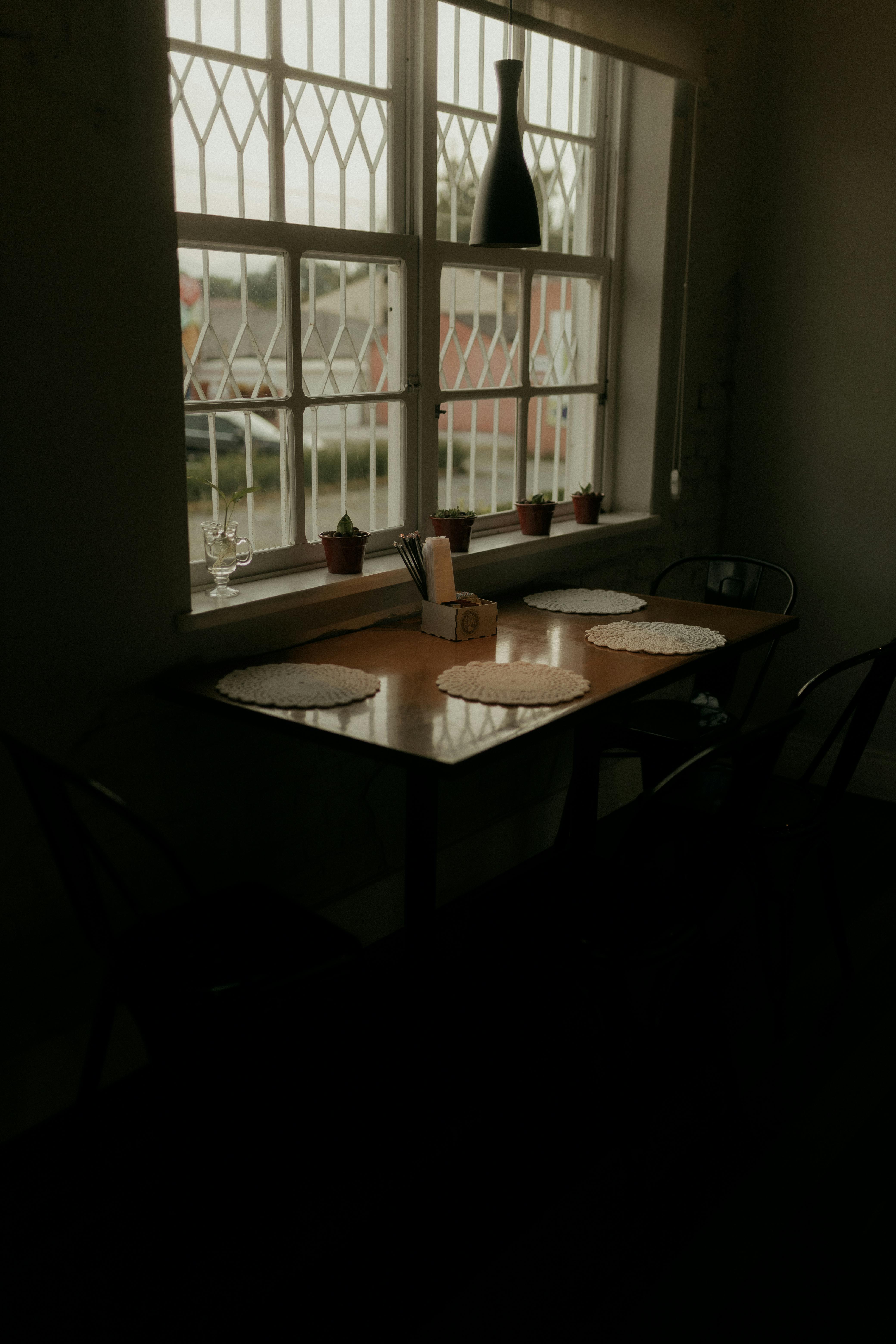 Free Warm and inviting dining table setup by a window with natural light and decorative wine bottle. Stock Photo