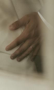Close shot of a hand wearing a wedding ring gently placed on white fabric, conveying intimacy.