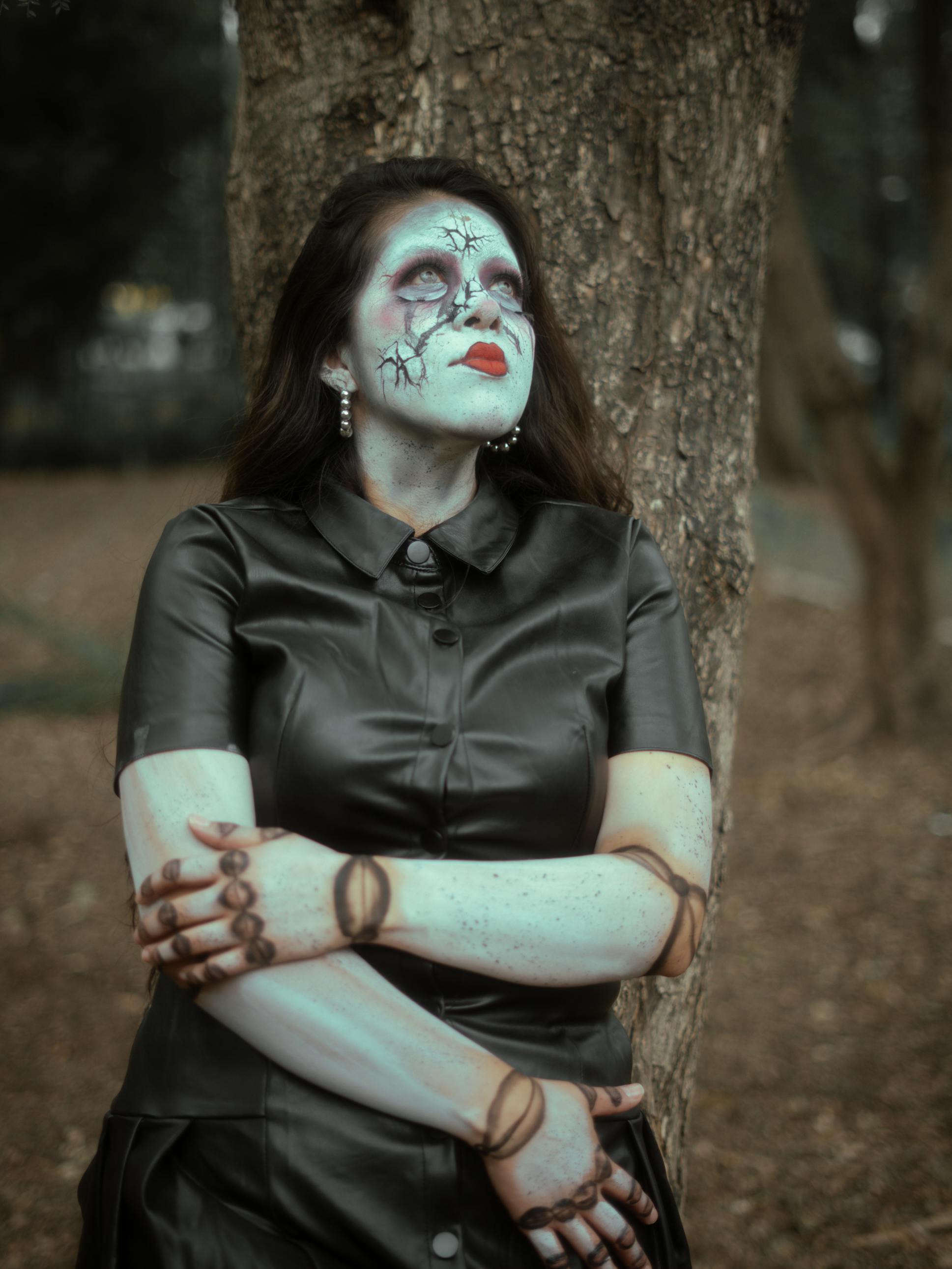 Gratis En kvinne i gotisk zombiesminke poserer utendørs mot et tre. Arkivbilde