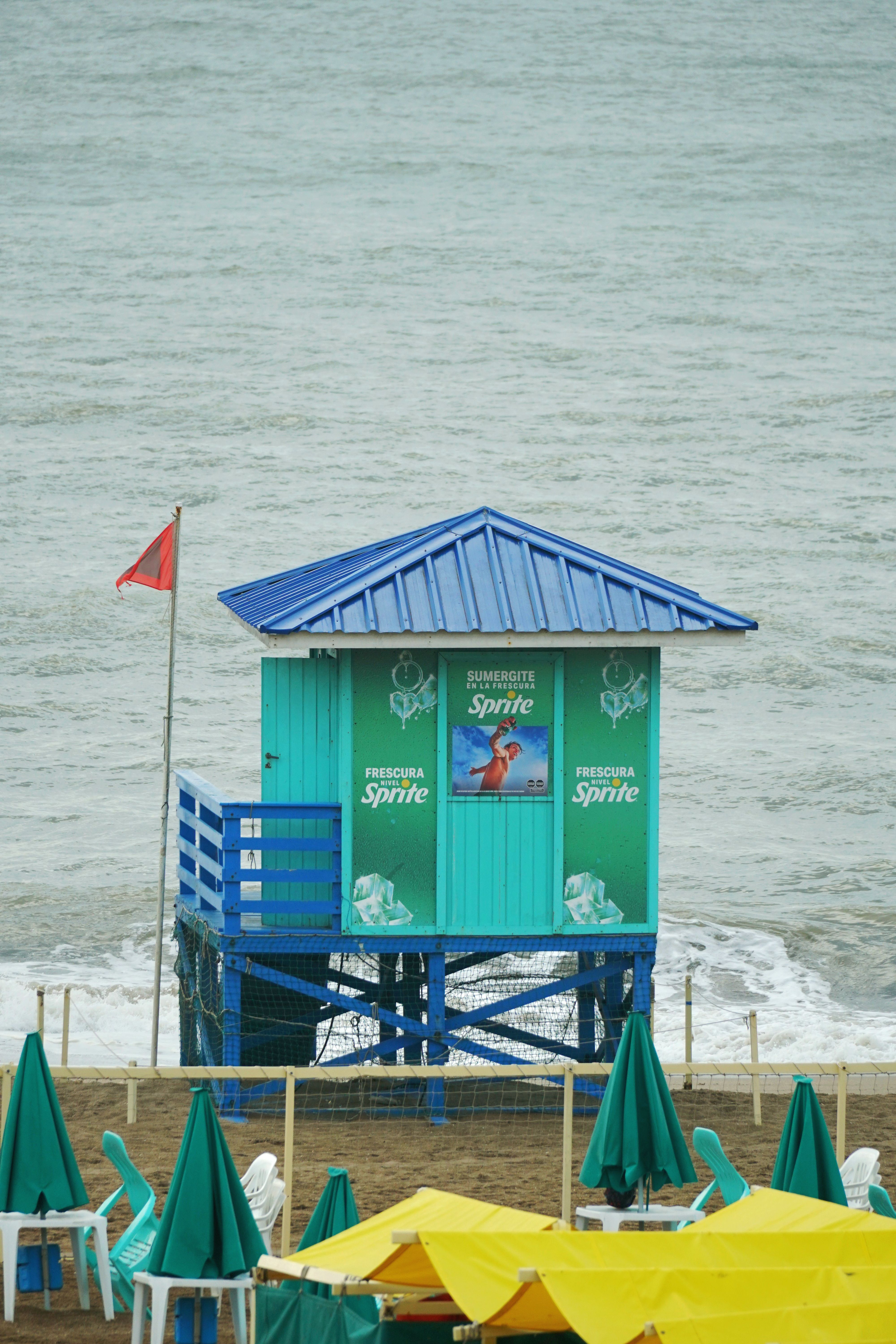 Bright lifeguard tower with advertisements on a cloudy day by the beach.