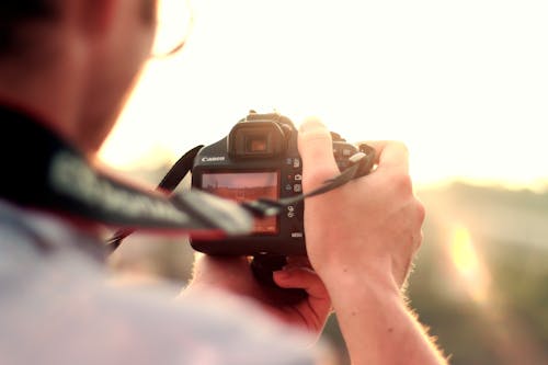 Free Man Holding Black Dslr Camera Standing in Front of the Sun Stock Photo