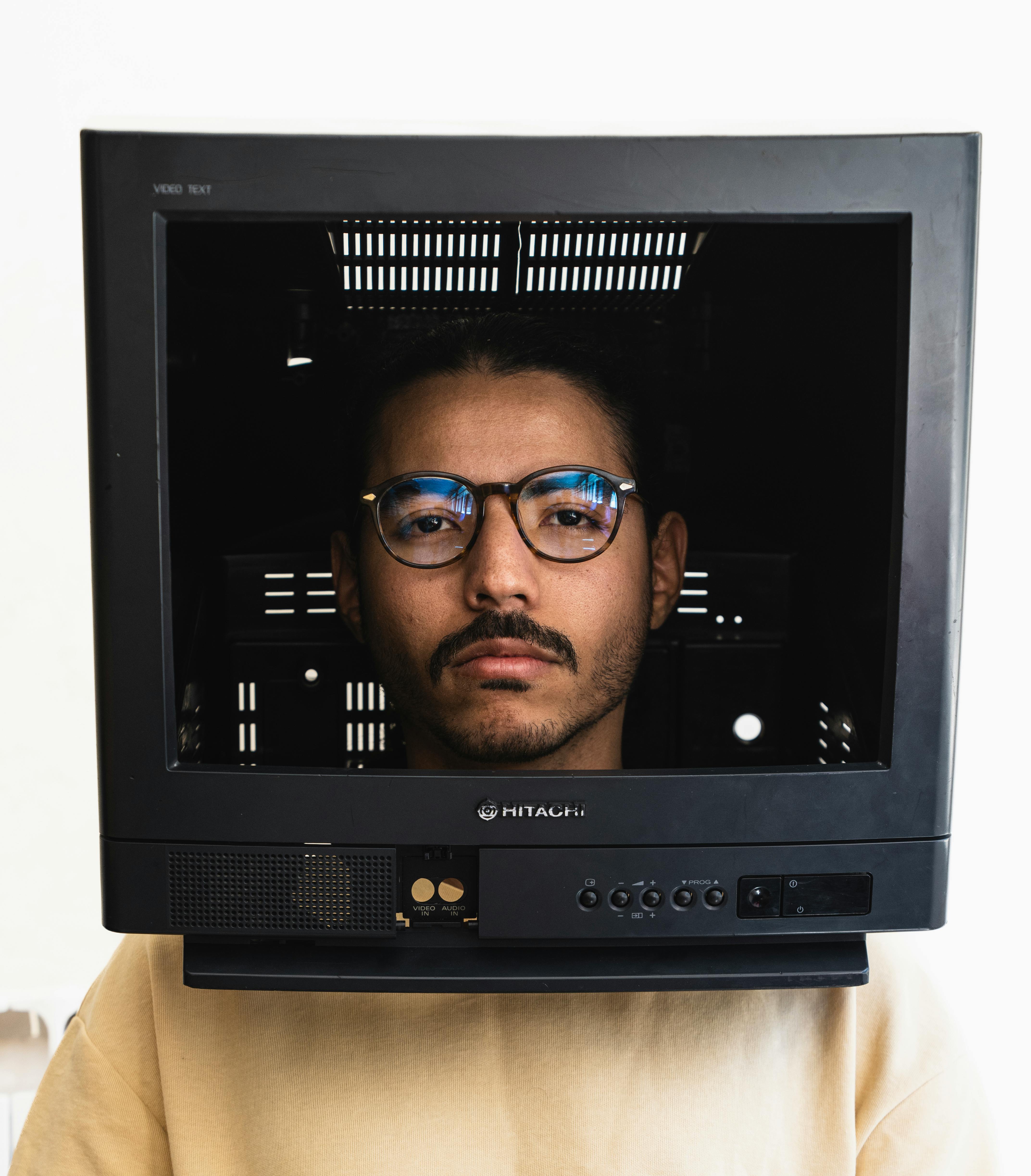 Gratis Un uomo guarda attraverso la cornice di un televisore d'epoca, fondendo la nostalgia analogica con la ritrattistica moderna. Foto a disposizione