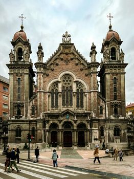 A grand church facade in Oviedo, showcasing architectural beauty with bustling pedestrians.