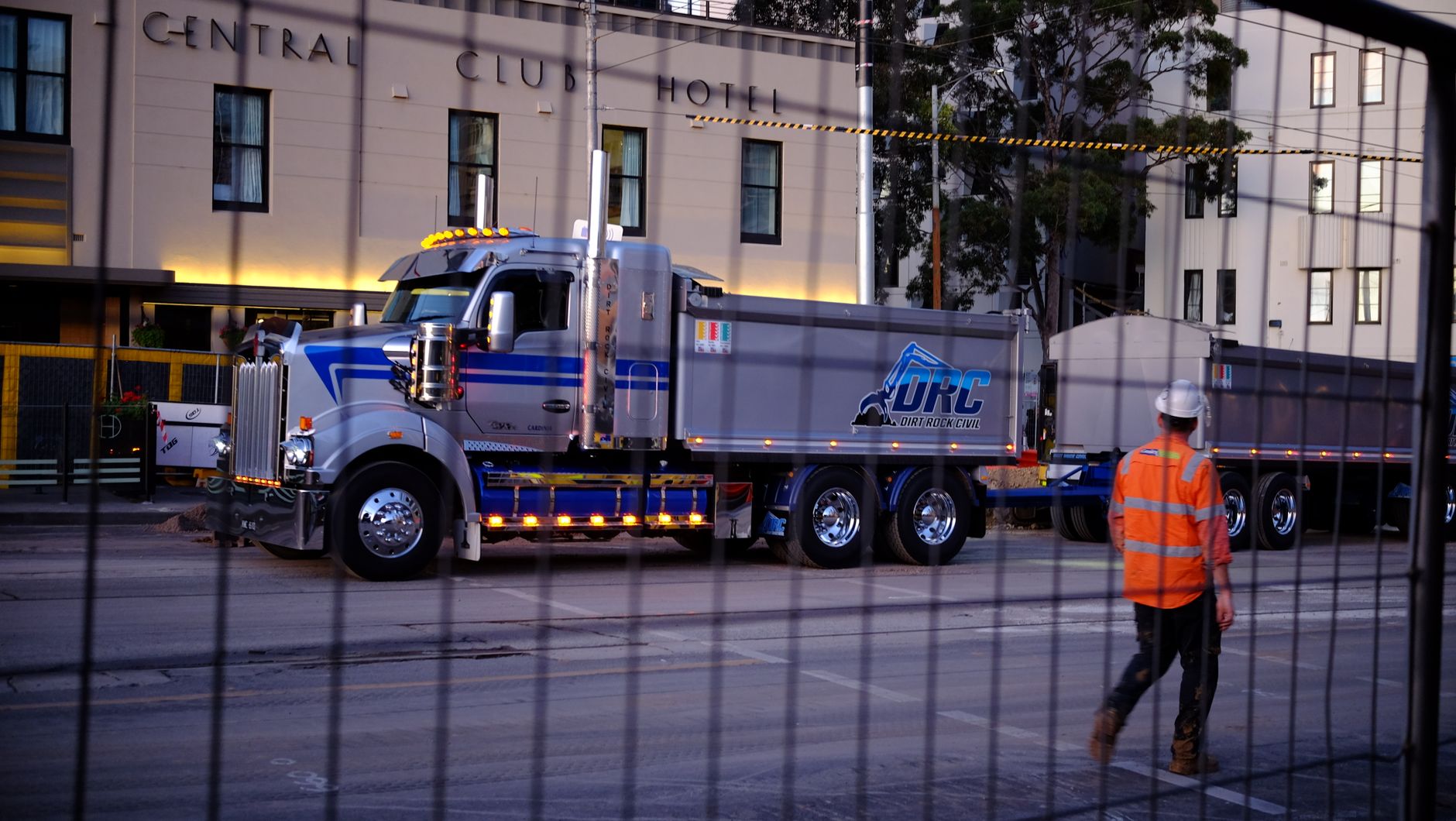 Construction worker in high-visibility workwear beside a truck at an evening worksite in Melbourne