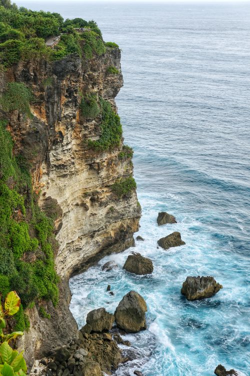 Free Majestic rocky escarpment with lush greenery overlooking the ocean waves crashing below. Stock Photo