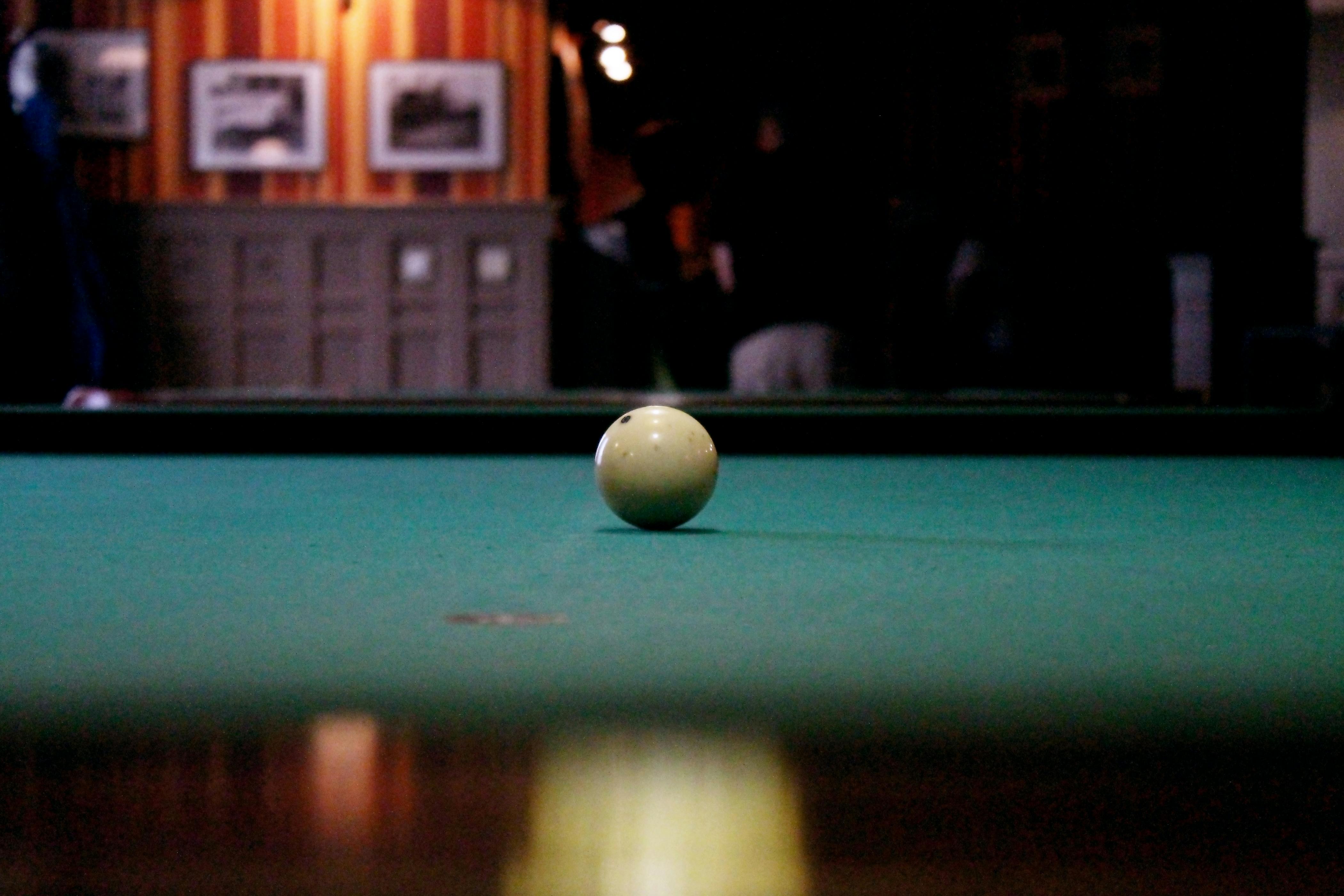 Gratuit Capture artistique d'une boule de billard sur une table de billard dans une pièce faiblement éclairée. Photos