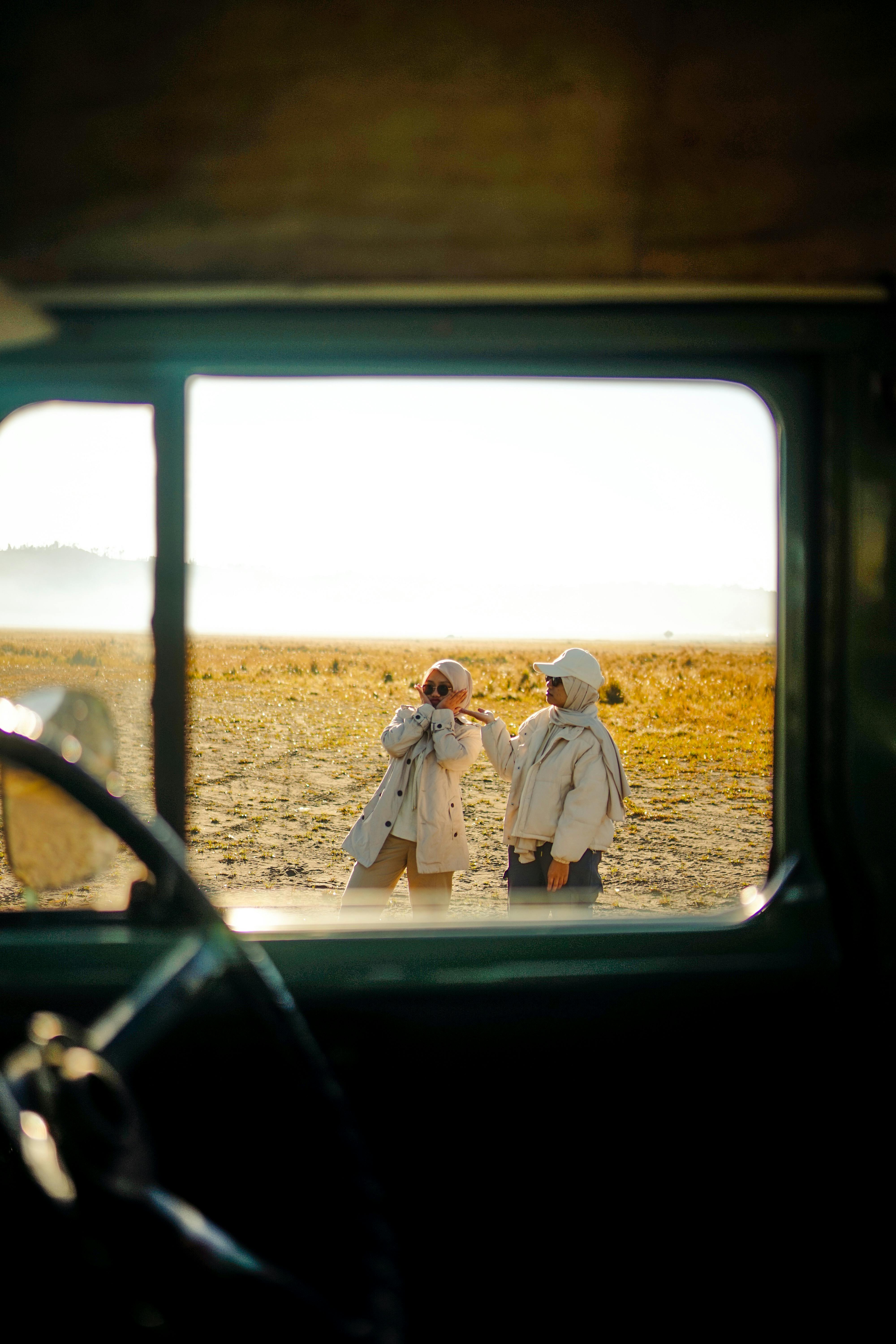 免费 透过老式汽车的车窗，拍摄到两名女子在东爪哇欣赏风景的画面。 素材图片