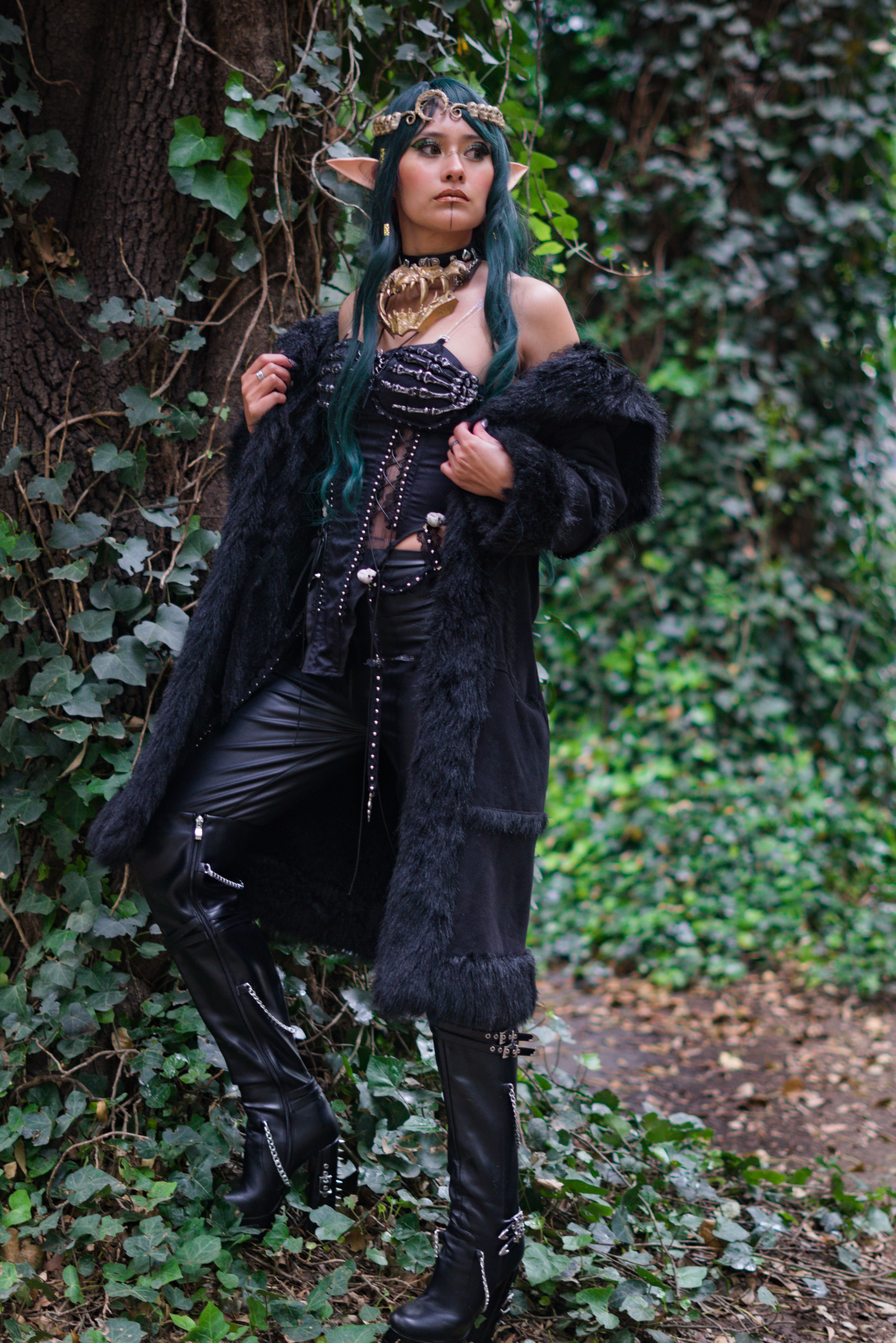 Elegant elf cosplayer posing in a mystical forest, wearing elaborate fantasy attire.