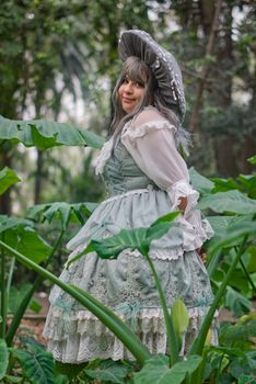 Woman wearing a vintage-style dress amidst lush green foliage.