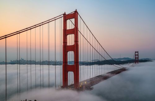 Free Golden Gate Bridge rising above fog during a colorful dusk in San Francisco Stock Photo