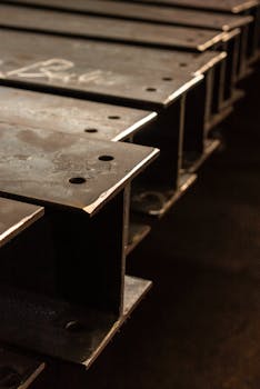 Close-up view of industrial steel I-beams stacked in a workshop.