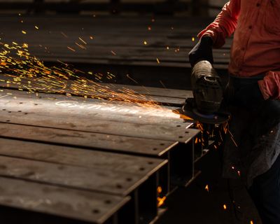 Worker grinding metal, finishing the surface