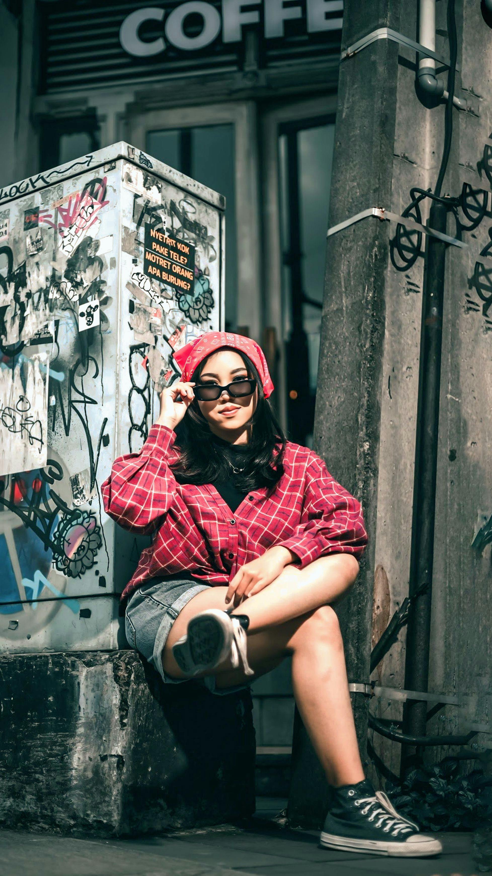 De franc Dona elegant posant en un entorn urbà ple de grafits amb una camisa de quadres. Foto d'estoc