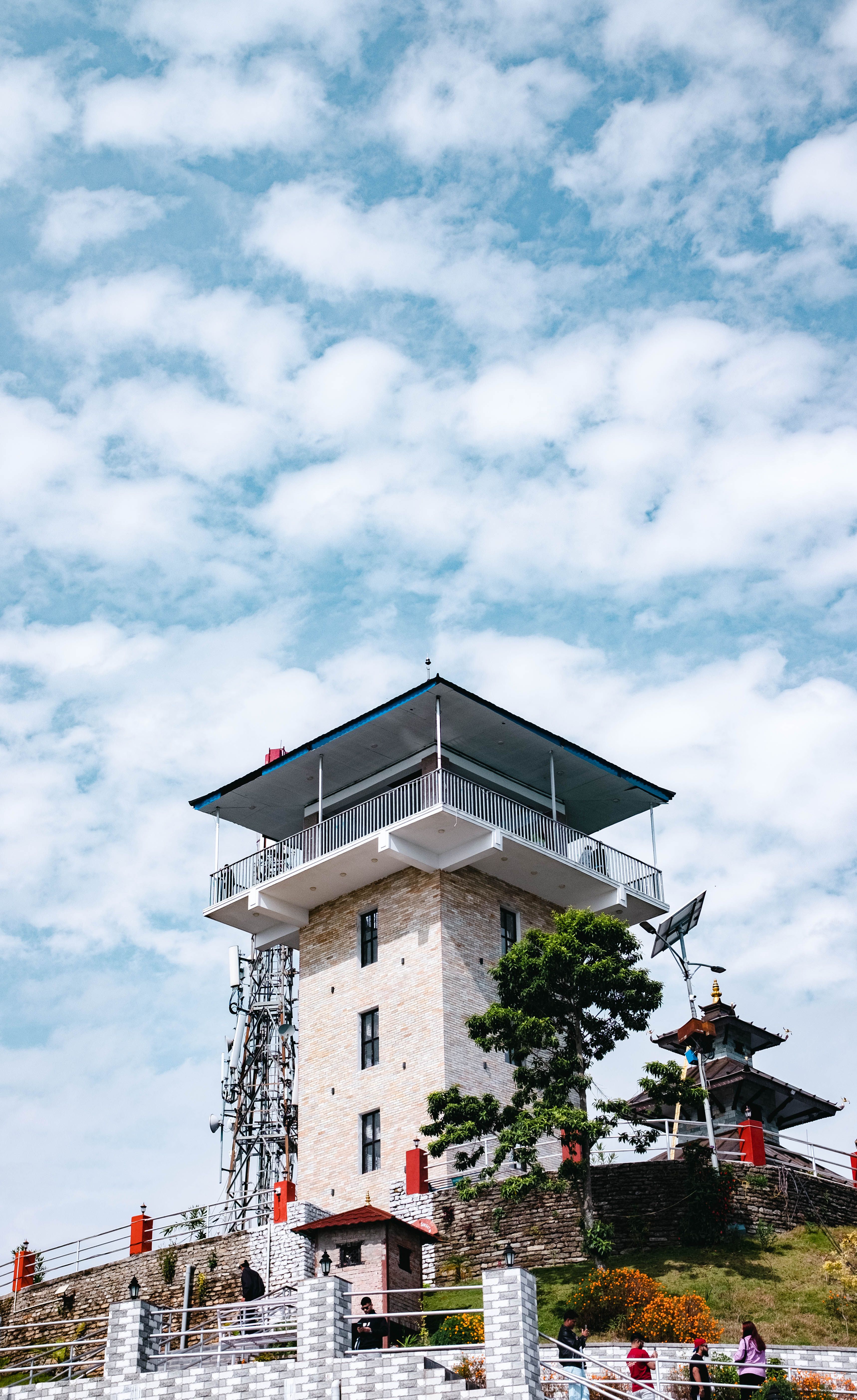 Historic tower with greenery under a vibrant sky in Nepal, capturing architectural beauty.