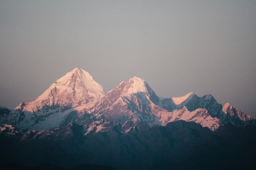 A breathtaking view of the Himalayan mountains bathed in soft sunrise light, revealing snow-capped peaks.
