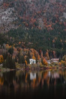 Tranquil autumn lakeside scene with colorful foliage and distant mountains reflecting on the water.