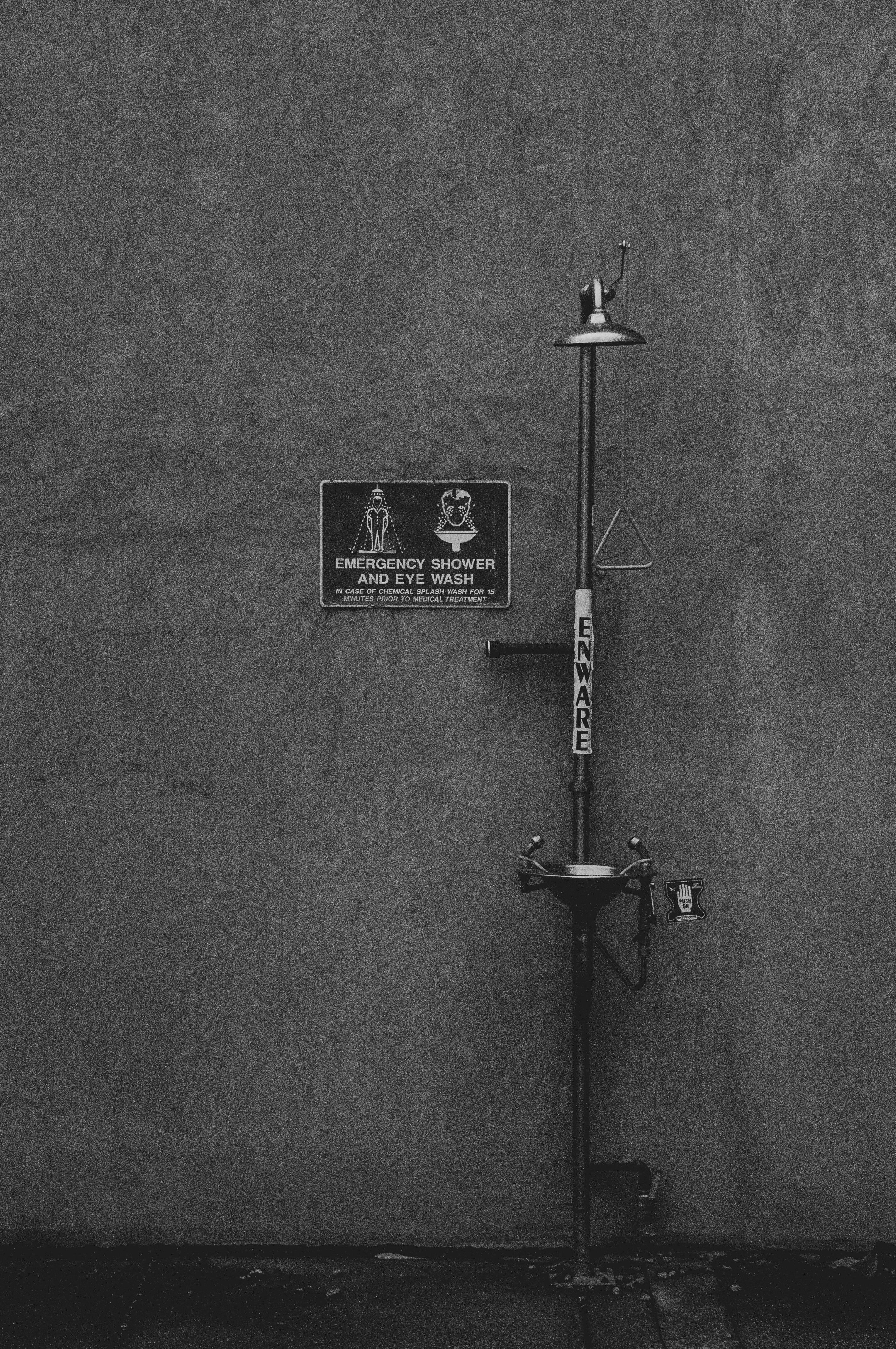 grátis Fotografia em preto e branco de um chuveiro de emergência e lava-olhos instalado em uma parede de concreto. Foto profissional