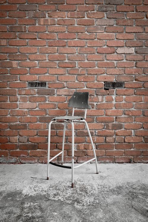 Free An old metal chair against a brick wall creates a rustic vibe. Stock Photo