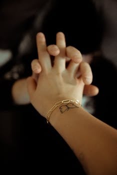 这是一张双手交织在一起的特写镜头，手镯和纹身点缀其中，象征着联系与团结