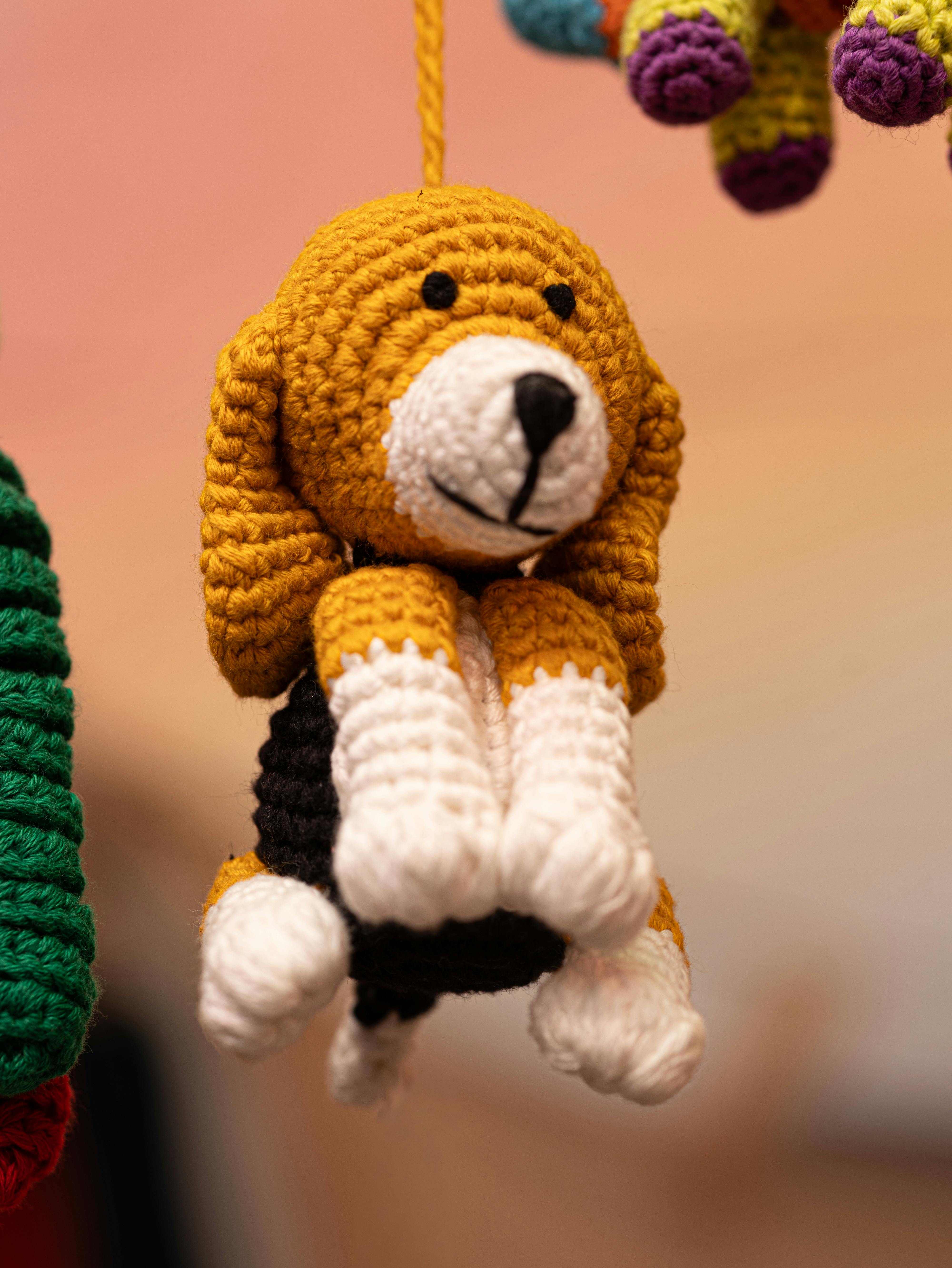 grátis Encantador brinquedo de crochê em formato de cachorro em tons quentes, perfeito para decoração de casa ou para o quarto de brinquedos das crianças. Foto profissional