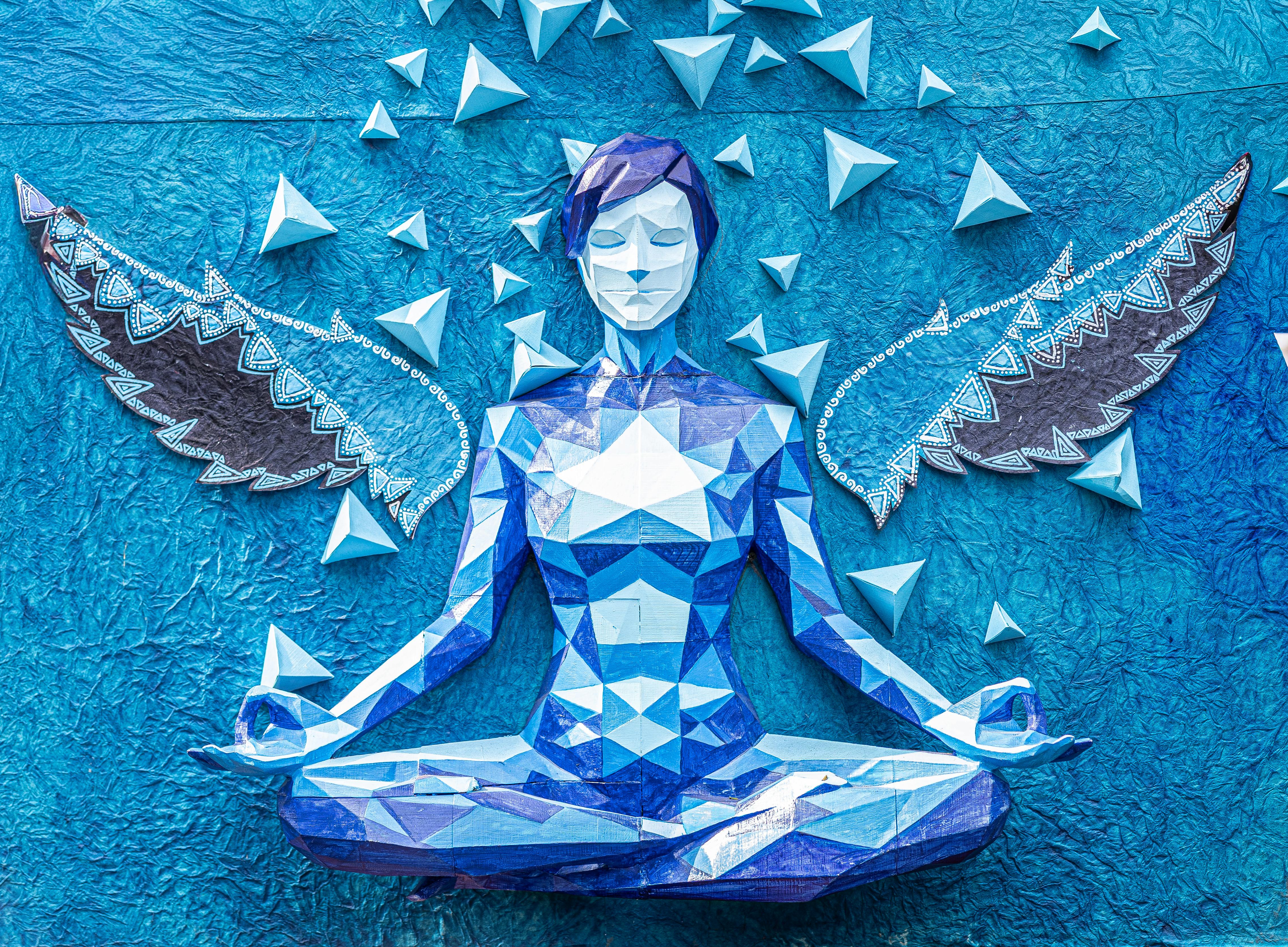 Vibrant blue origami angel sculpture in yoga pose with decorative wings and geometric design