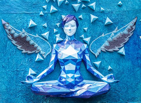 Vibrant blue origami angel sculpture in yoga pose with decorative wings and geometric design