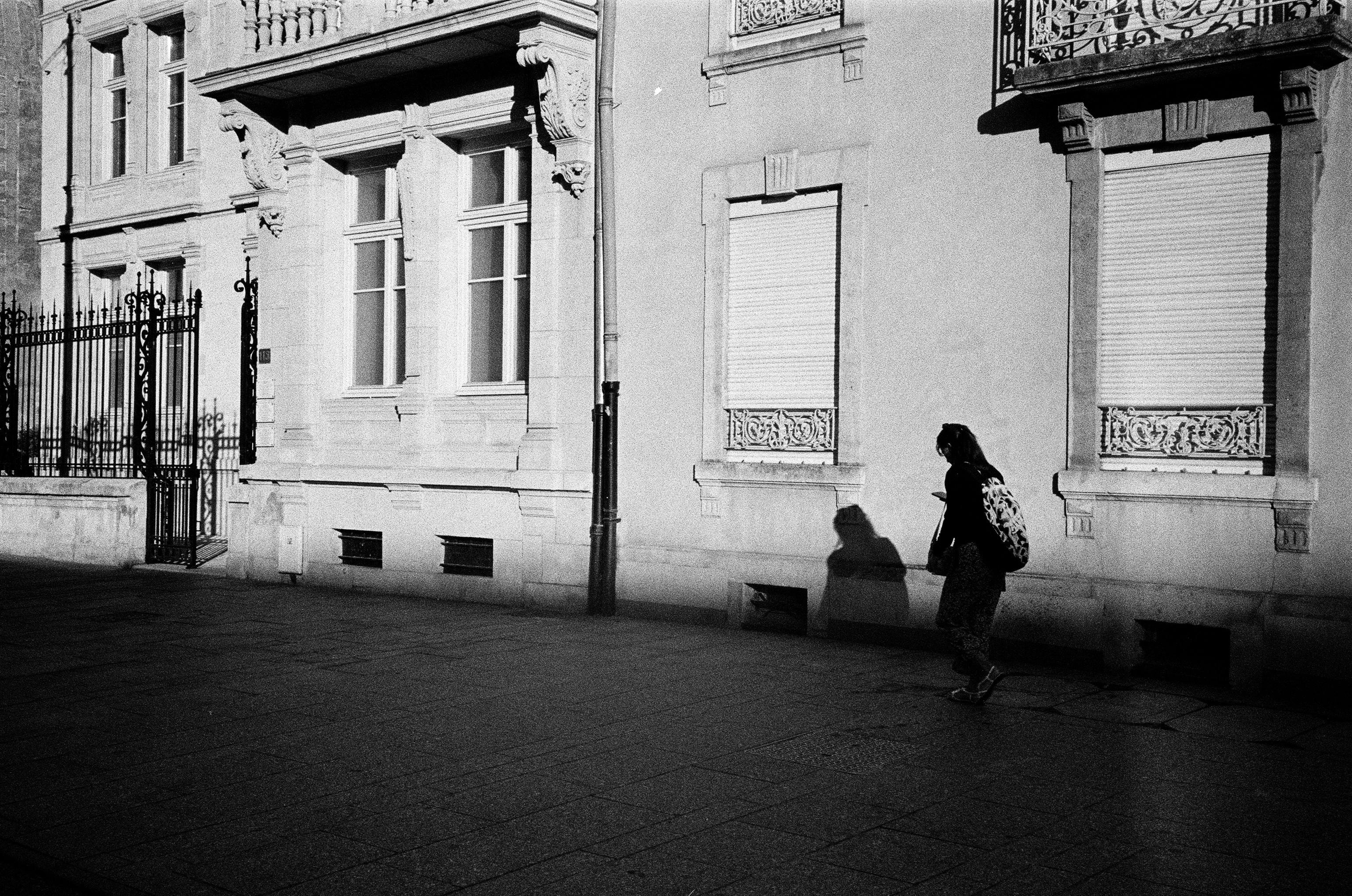 Gratis Scena di strada d'epoca con un camminatore solitario a Nancy, in Francia, con ombre forti sullo sfondo dell'architettura classica. Foto a disposizione