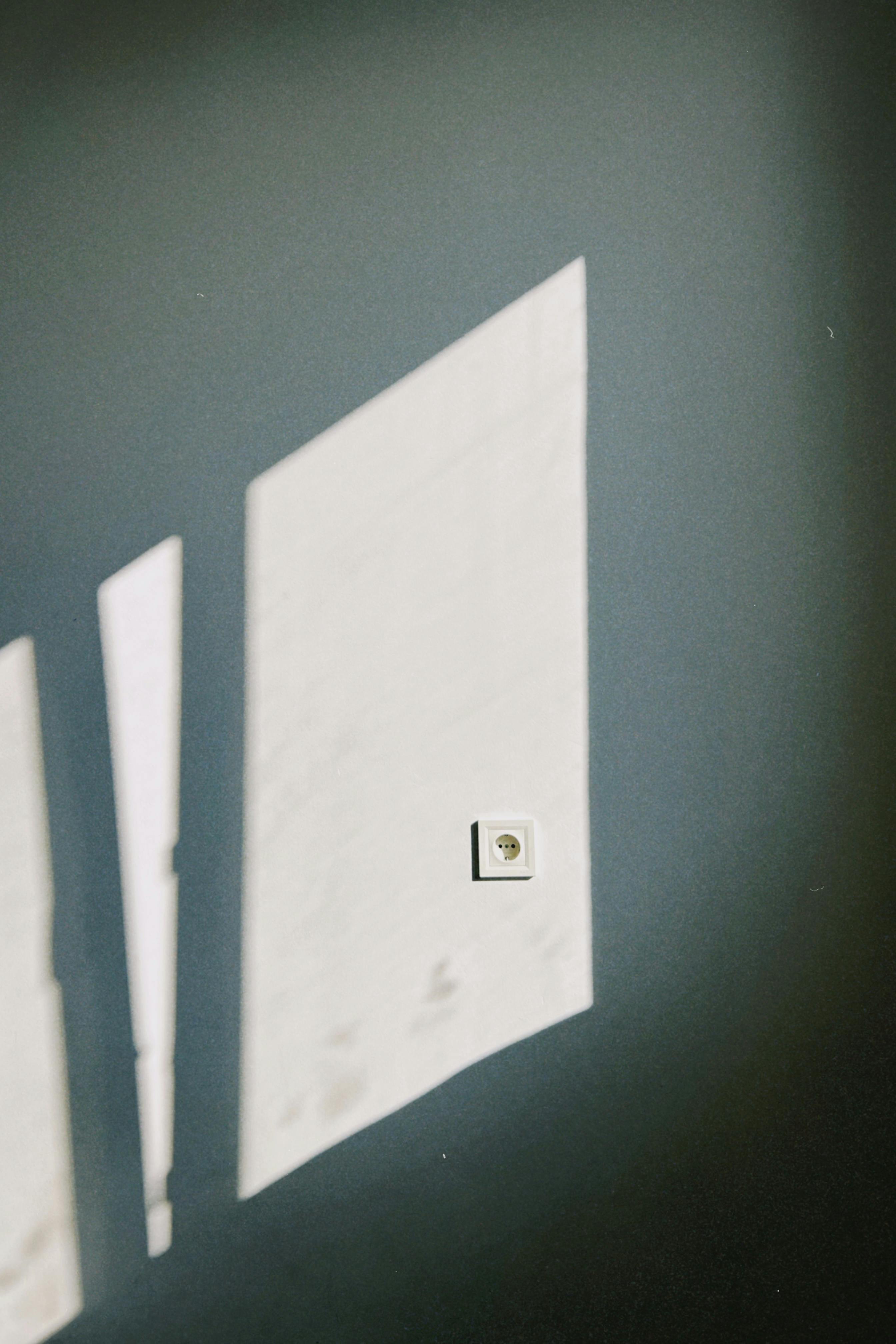 De franc Ombra artística de la llum d'una finestra a la paret amb un interruptor, creant un ambient minimalista. Foto d'estoc