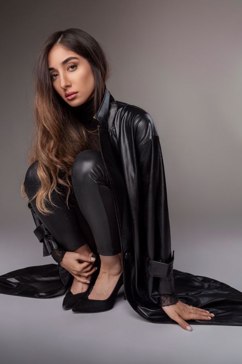 Free Elegant woman posing in chic black leather outfit against neutral background. Stock Photo