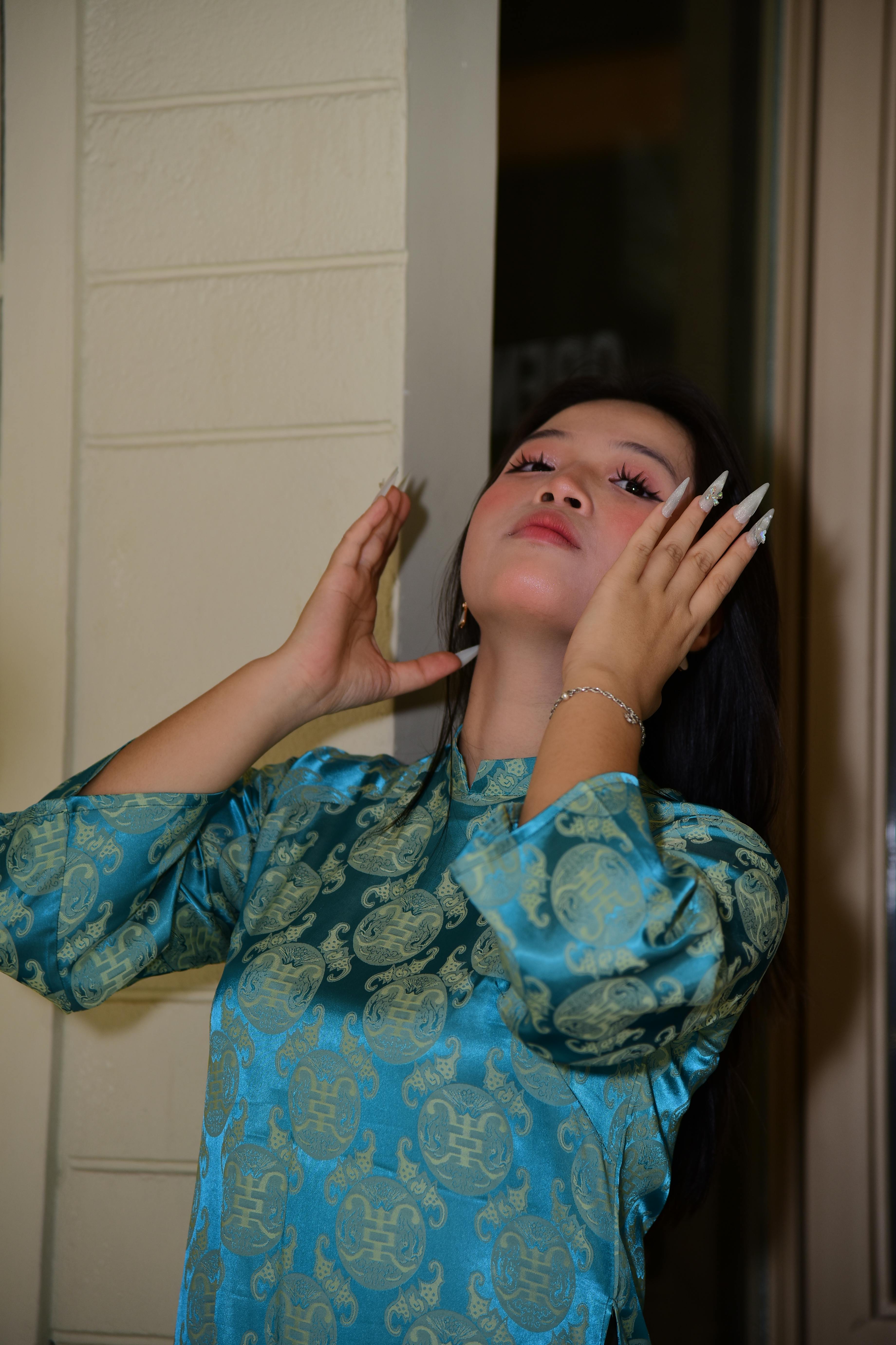 Gratis Elegante ritratto di una donna in un abito tradizionale blu con motivi intricati, scattato in un interno. Foto a disposizione