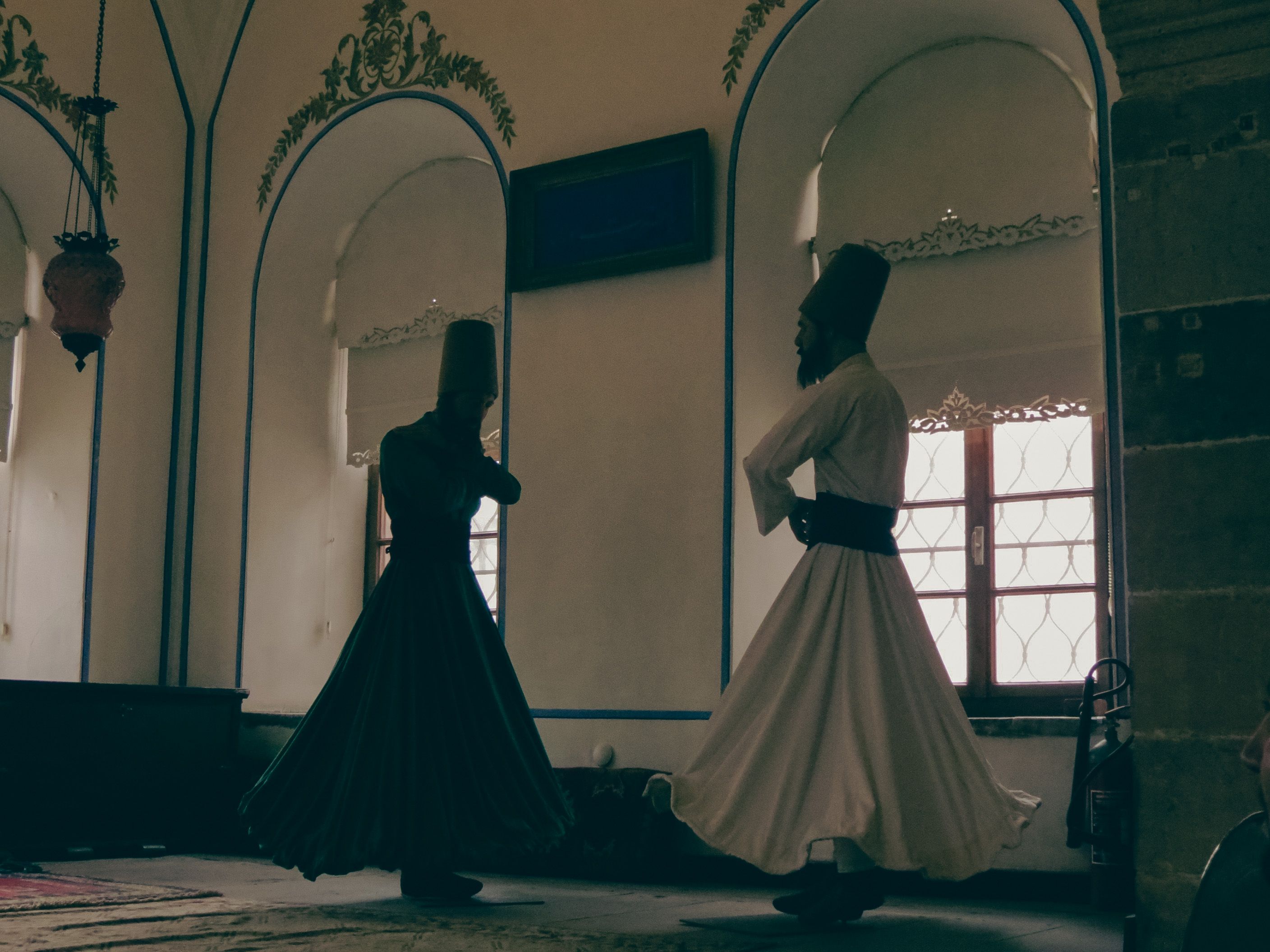 Two whirling dervishes perform in a traditional setting in Konya, Türkiye, showcasing Sufi culture.