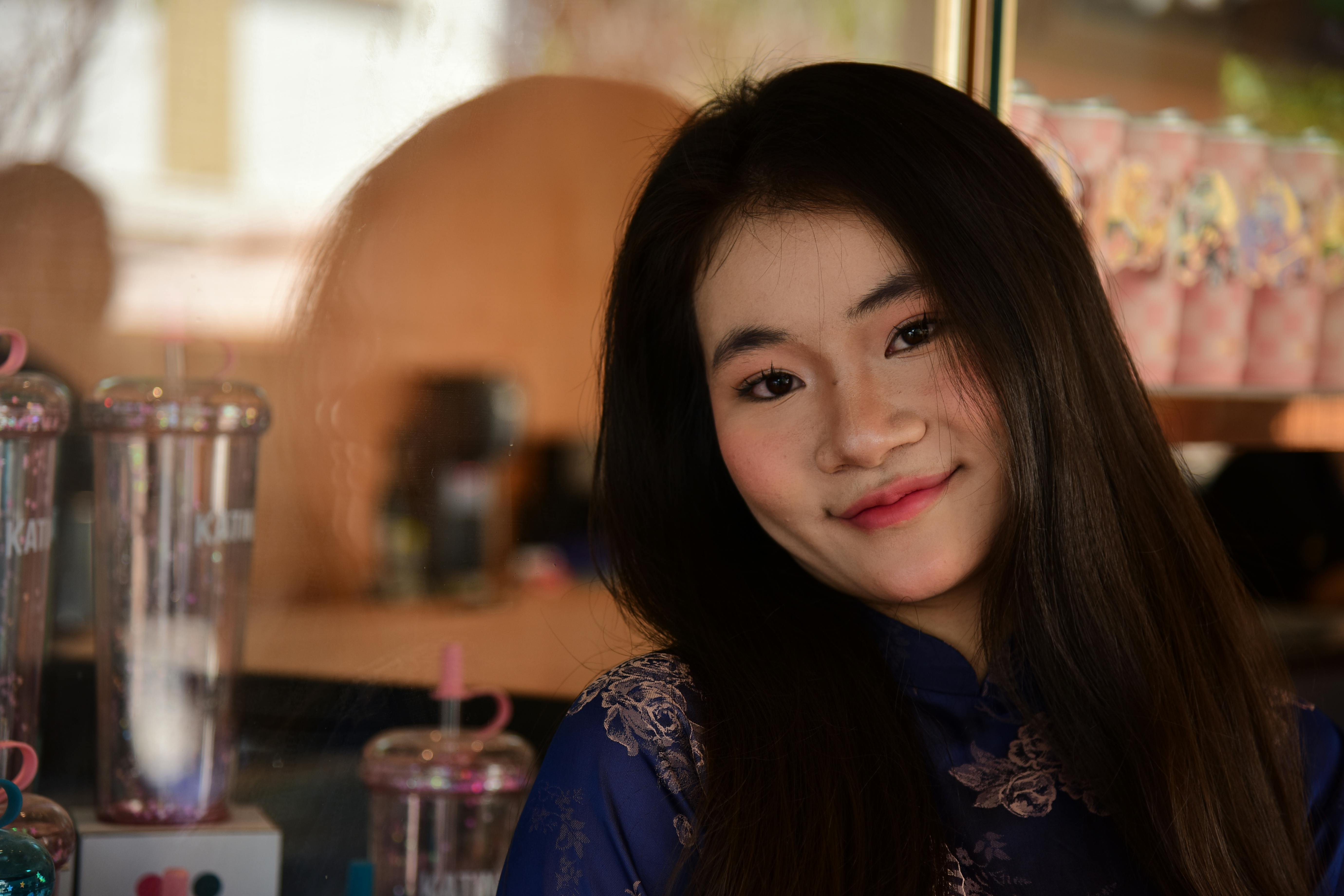 Ücretsiz Kafe ortamında, mavi çiçekli bir bluz giymiş ve gülümseyen genç bir kadının portresi. Stok Fotoğraflar