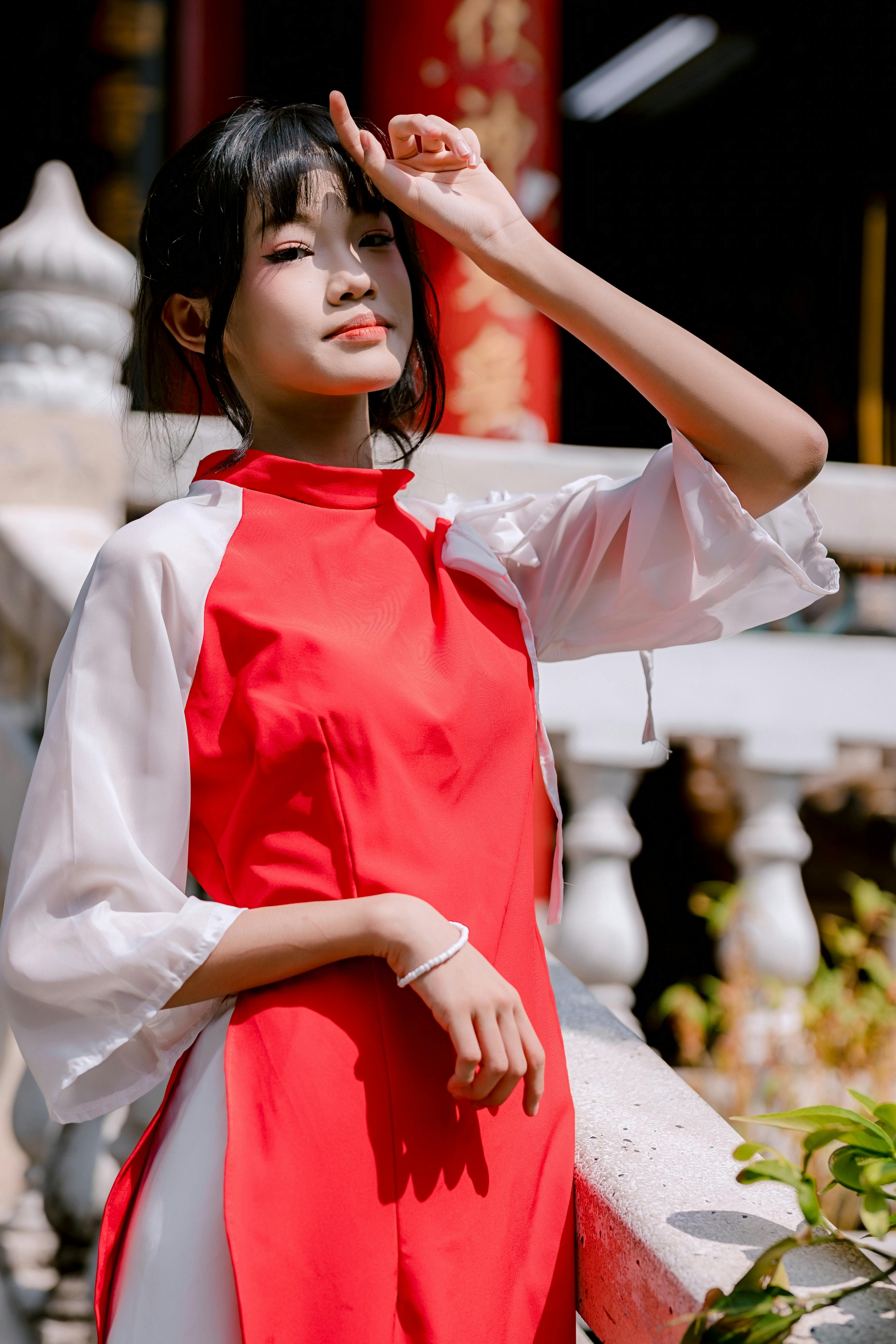Ücretsiz Açık havada güneş altında geleneksel kırmızı ve beyaz elbise giyen Asyalı bir kadın. Stok Fotoğraflar