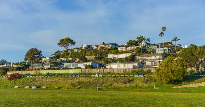 Modern California homes on a hillside under a clear blue sky