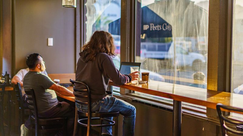 Two young adults enjoy a quiet moment in a coffee shop with warm natural lighting.