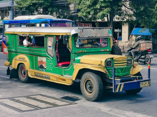 Free Iconic Philippine jeepney parked on a busy urban street, showcasing vibrant local transport culture. Stock Photo