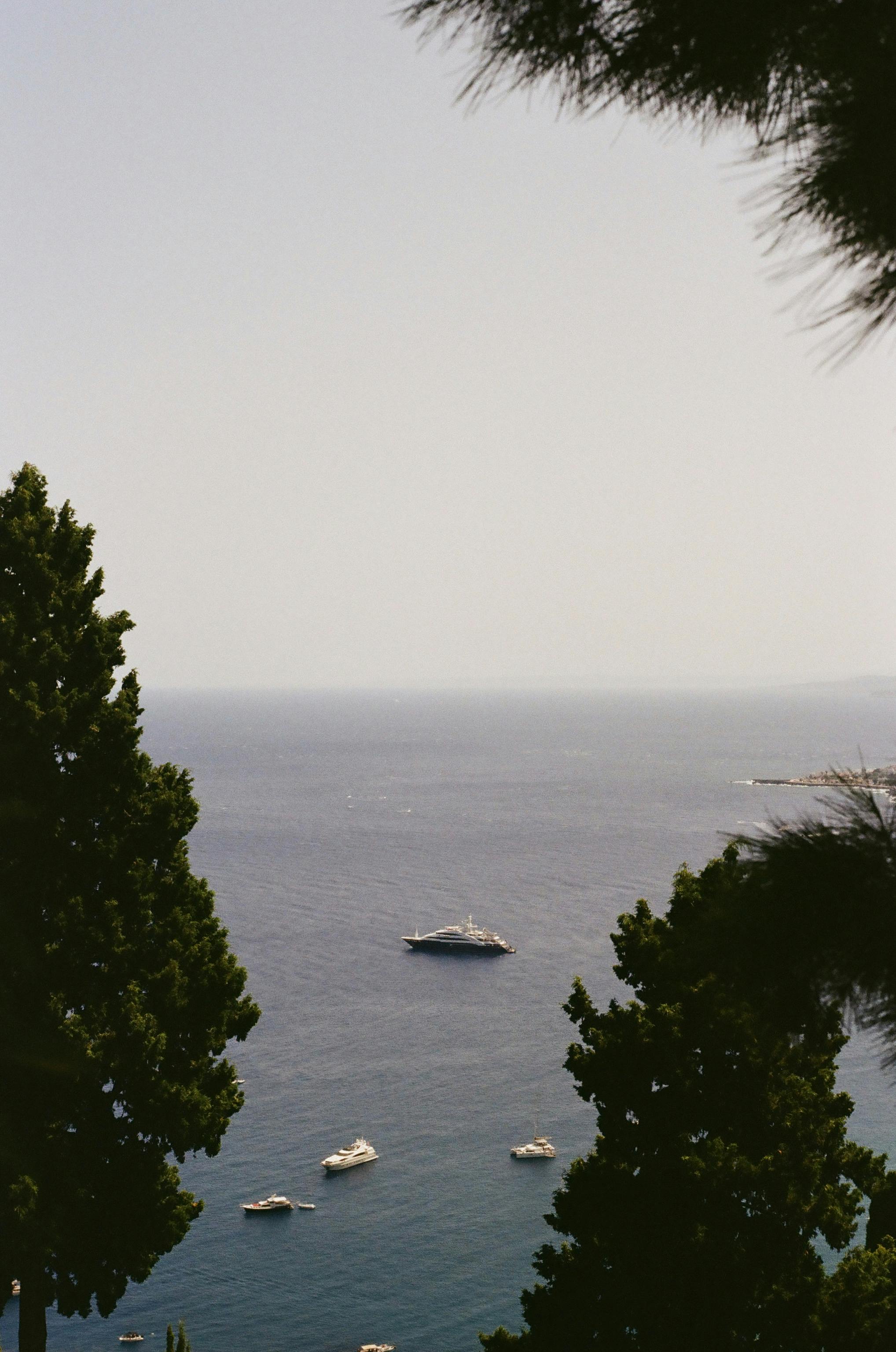 Ücretsiz Sicilya'nın Taormina açıklarındaki sakin sularda, yemyeşil bitki örtüsüyle çevrili yatların nefes kesen manzarası. Stok Fotoğraflar