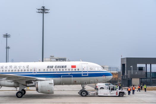 Air China airplane being maneuvered on the runway by ground staff at an airport.