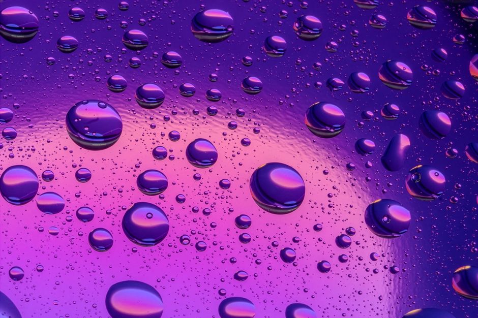 Abstract image of water droplets on a vibrant purple and pink surface, creating a modern artistic effect.