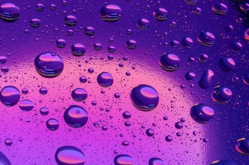 Free Abstract image of water droplets on a vibrant purple and pink surface, creating a modern artistic effect. Stock Photo