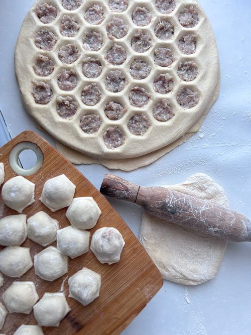Free Close-up of traditional Russian pelmeni being prepared with a rolling pin and cutting board. Stock Photo
