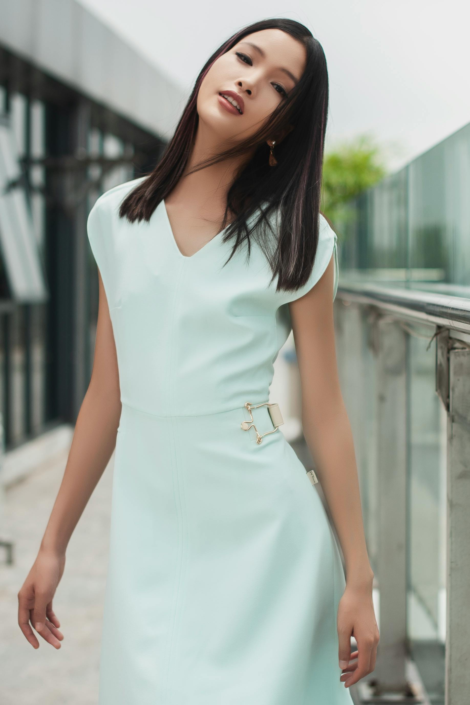 Gratis Donna elegante che posa con un abito azzurro sullo sfondo di un moderno contesto urbano. Foto a disposizione