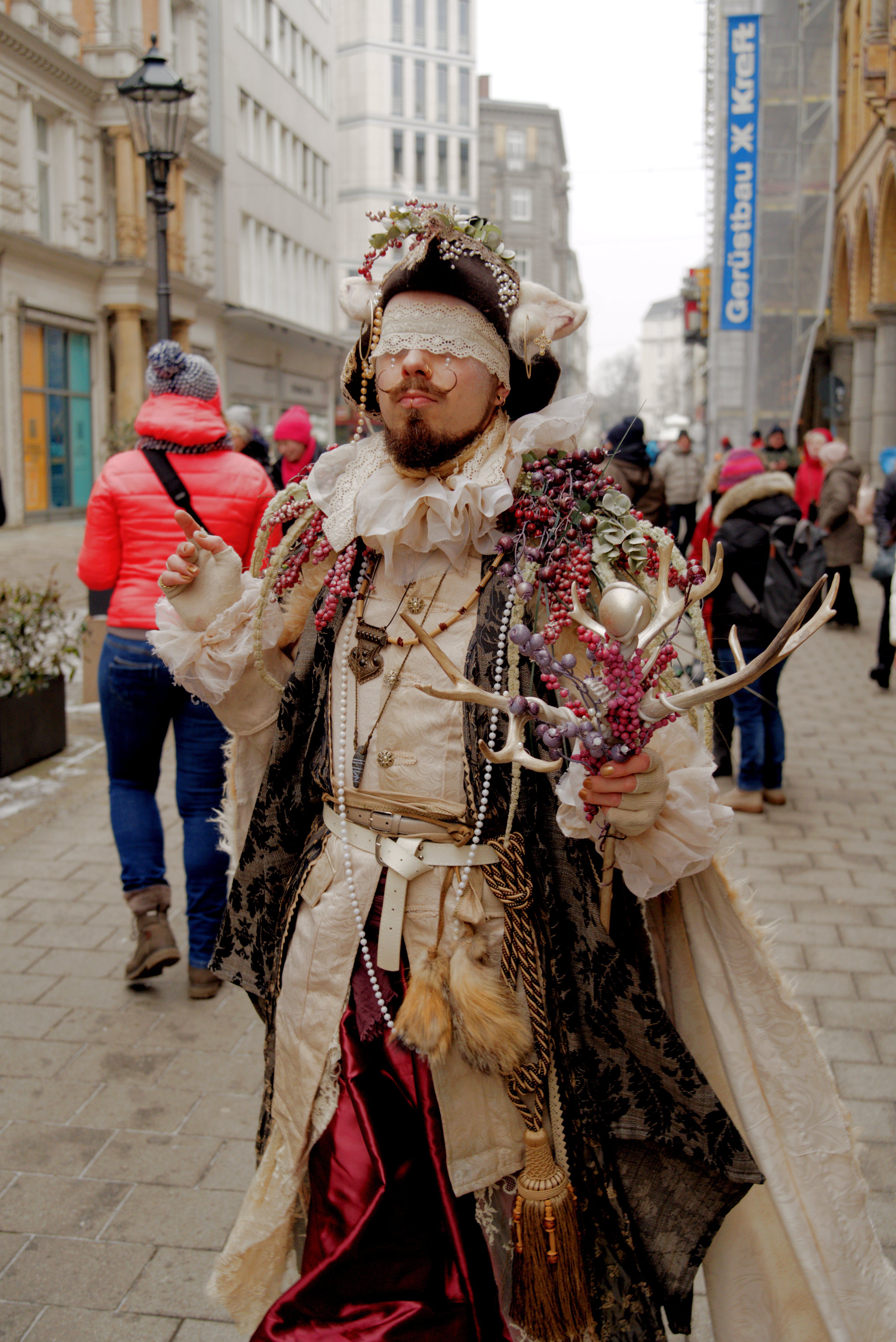 A street performer in an ornate festival costume on a winter day in a European city.