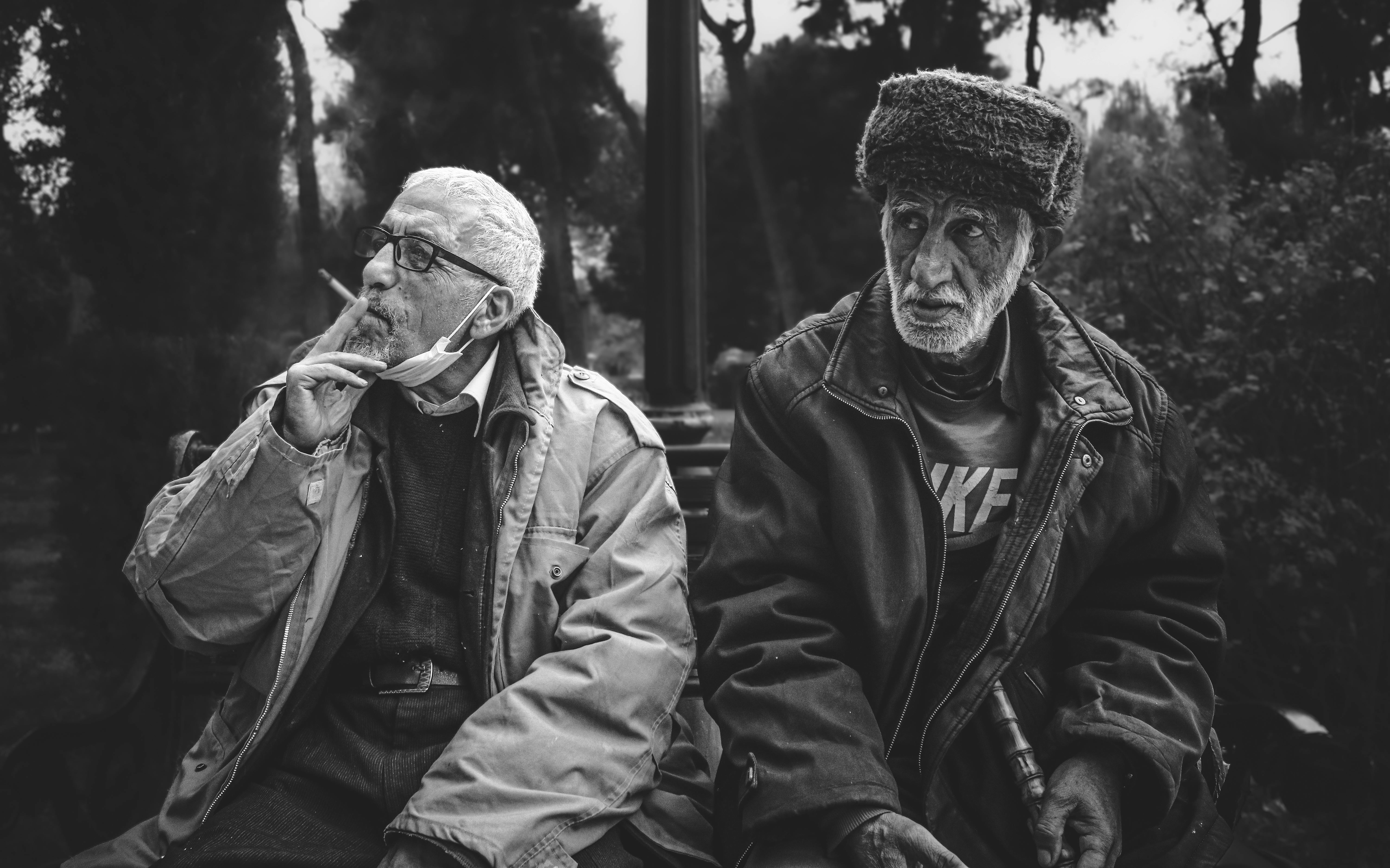 Gratis Due uomini anziani condividono un momento di contemplazione in un parco, immortalati in bianco e nero per un effetto senza tempo. Foto a disposizione