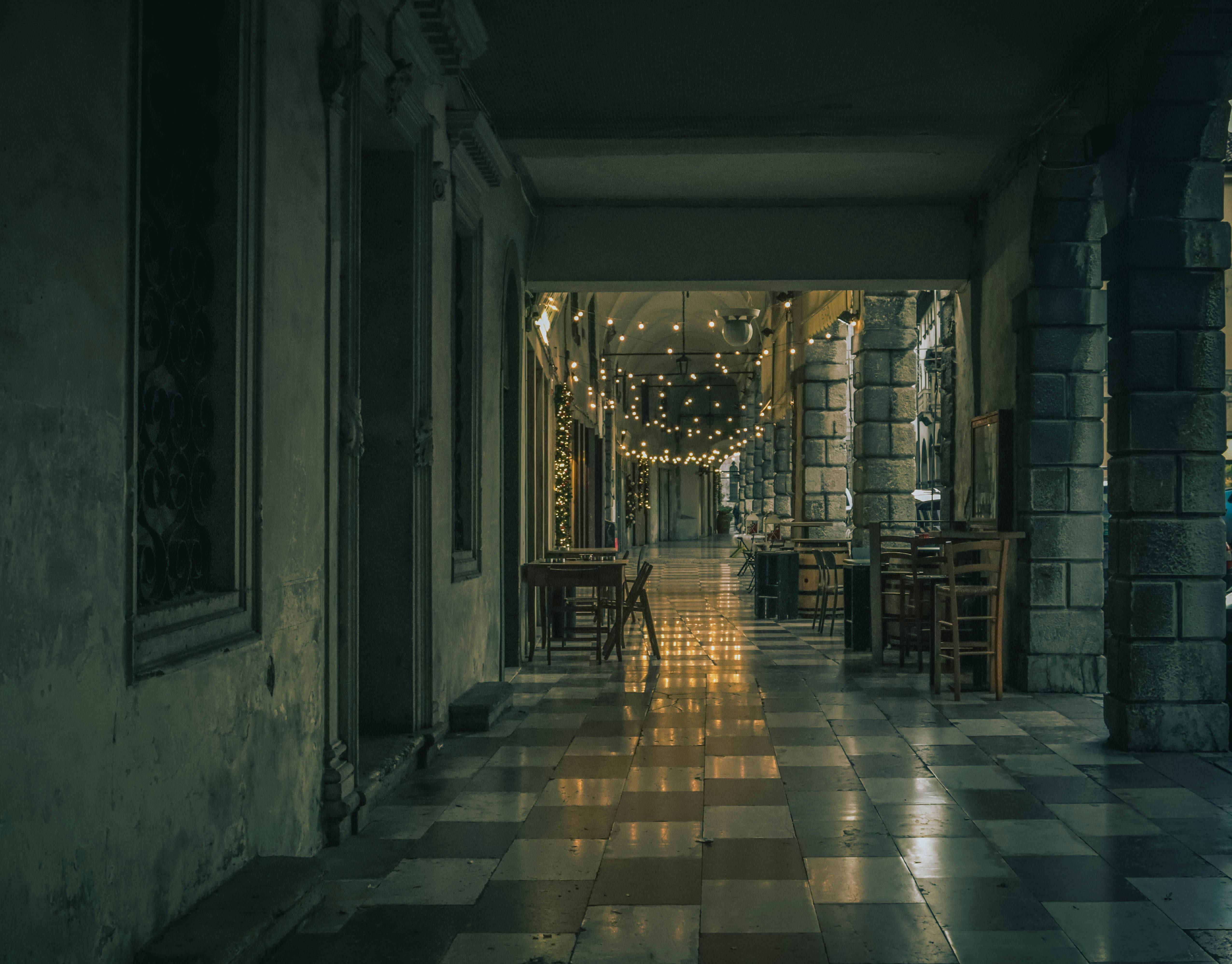 Gratuit O curte senină, slab luminată, împodobită cu ghirlande luminoase și mese goale, creând o atmosferă mohorâtă. Fotografie de stoc