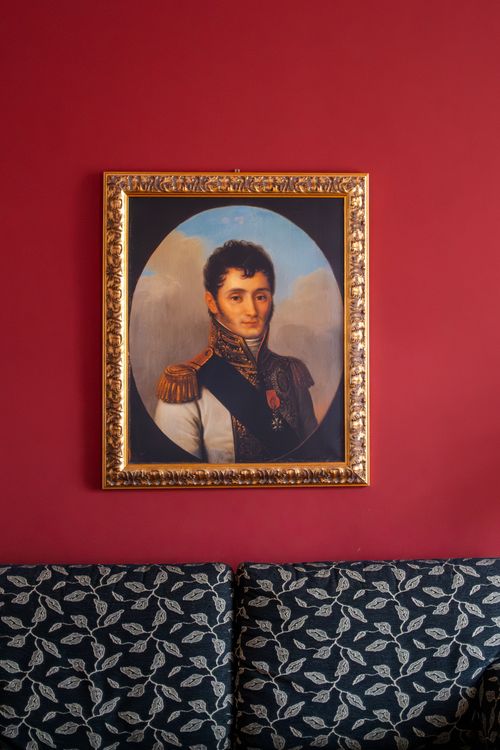 Free A framed historical portrait on a red wall above a patterned couch. Stock Photo