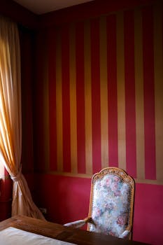 Atmospheric vintage room with floral chair and red striped wallpaper, perfect for an elegant setting.